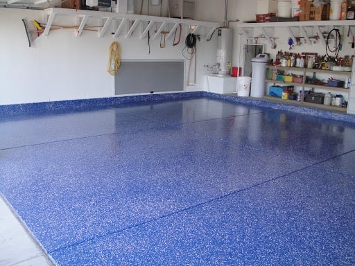 Clean garage with shiny blue epoxy floor and organized pegboard wall with tools and supplies