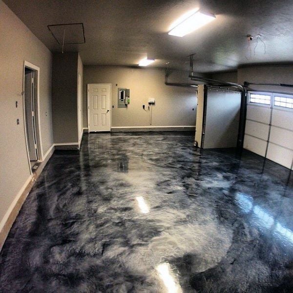 Spacious garage interior with polished concrete floor, white walls, fluorescent lighting, and a garage door visible on the right side