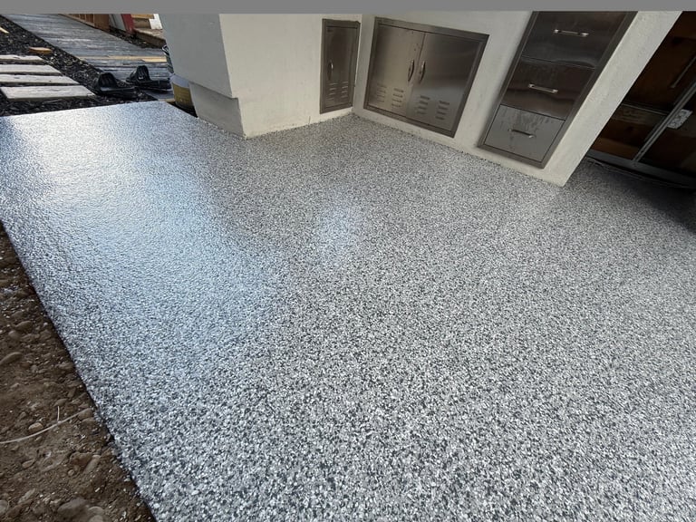 Showroom display of speckled gray epoxy flooring with various cabinet door samples on white walls