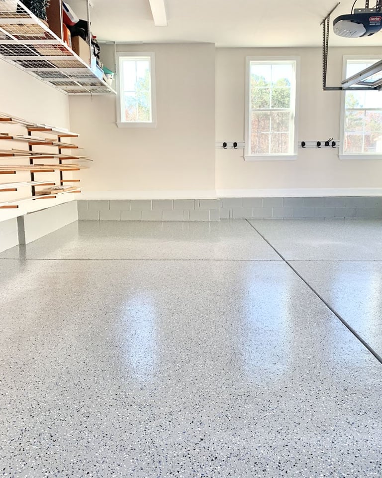 Modern garage interior with polished concrete floor, white walls, subway tile backsplash, wooden wall shelving, and windows
